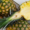 Ananas – halbiert – liegt in einem Korb mit ganzen Ananasfrüchten.