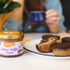 Ein Glas Seeberger Cashew-Kaffee Creme steht neben Schokolade-Desserts auf einem Teller.