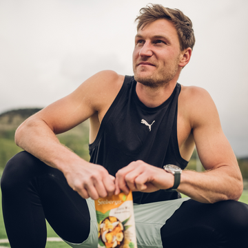 Ein Mann öffnet eine Tüte Seeberger Trockenfrüchte auf einem Sportplatz.